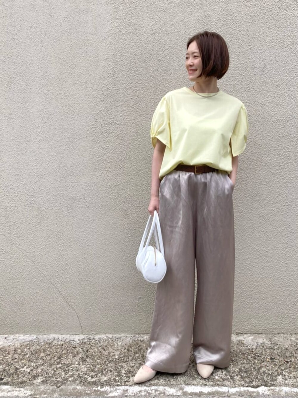 イエロー系のTシャツ/カットソー、ベージュ系のその他パンツ、ホワイト系のバッグを着用したレディースの夏コーディネートの4枚目の写真