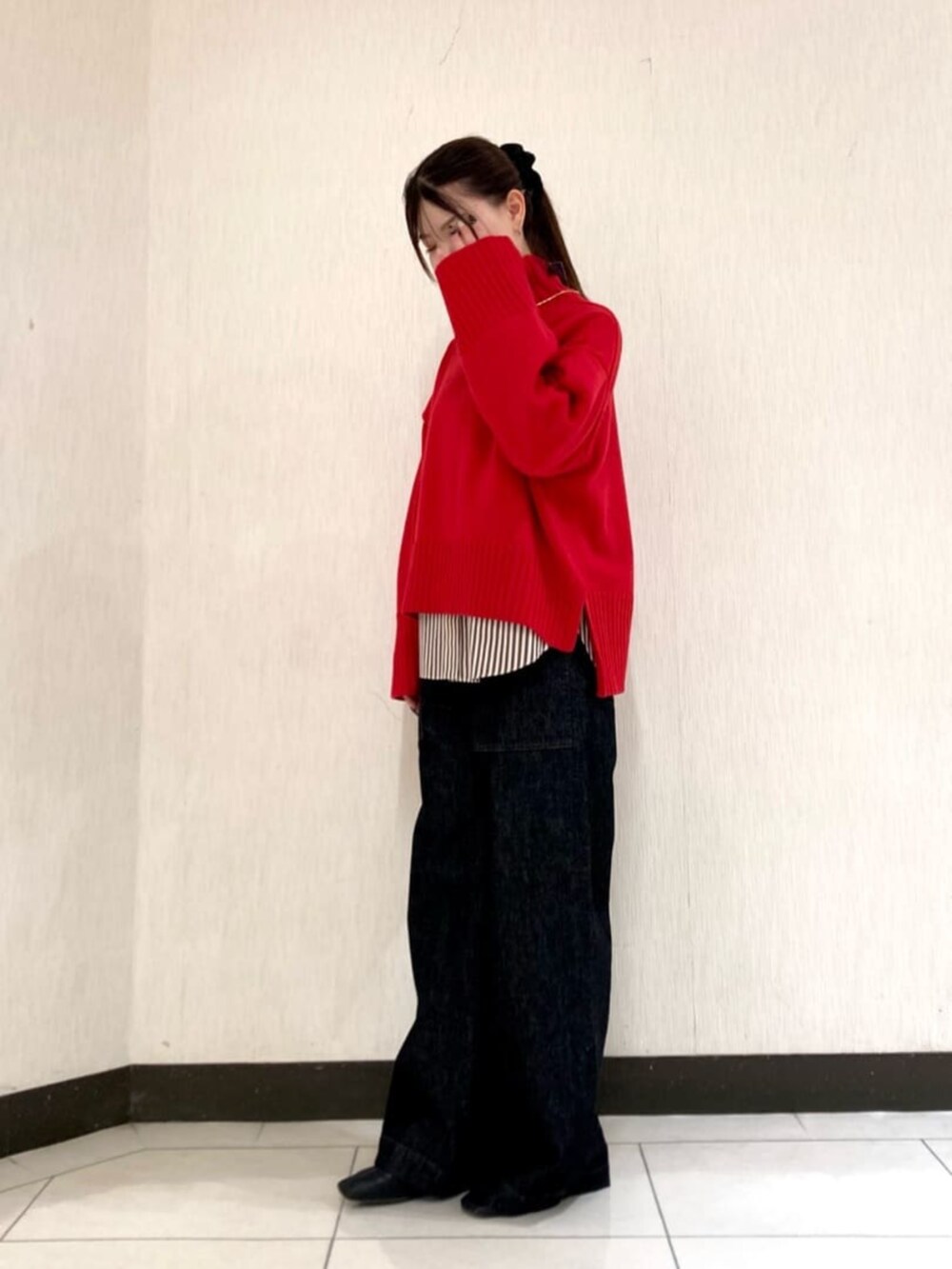 レッド系のニット/セーター、ブラック系のデニムパンツを着用したレディースの冬コーディネートの3枚目の写真