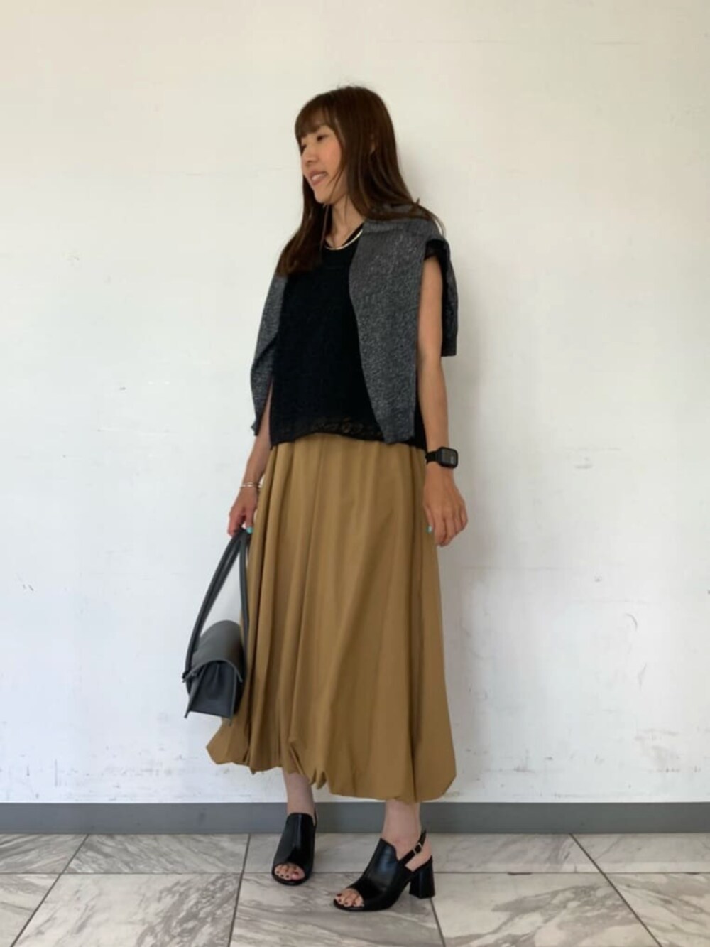 ブラック系のシャツ/ブラウス、ブラック系のサンダル、グレー系のスカートを着用したレディースの春コーディネートの3枚目の写真