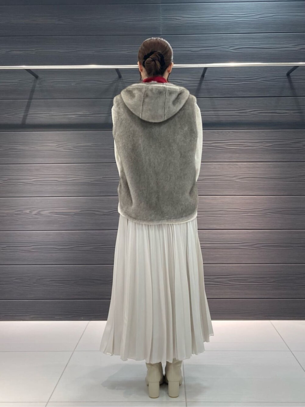 ベージュ系のベスト、ホワイト系のブーツ、ホワイト系のスカートを着用したレディースの秋コーディネートの7枚目の写真