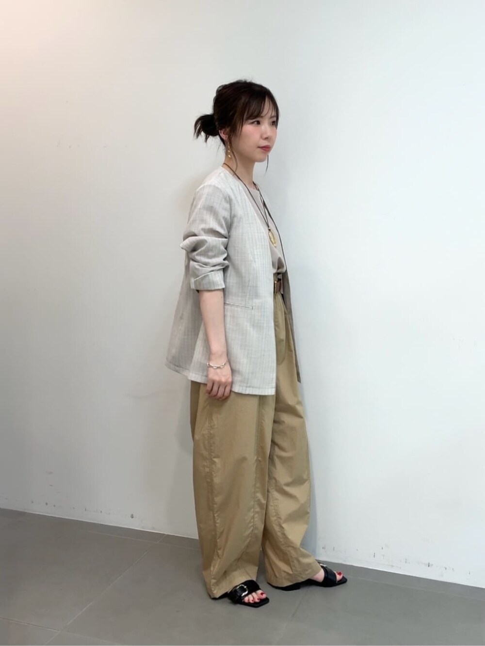 ホワイト系のノーカラージャケット、ベージュ系のその他パンツ、ブラウン系のベルトを着用したレディースの夏コーディネートの2枚目の写真