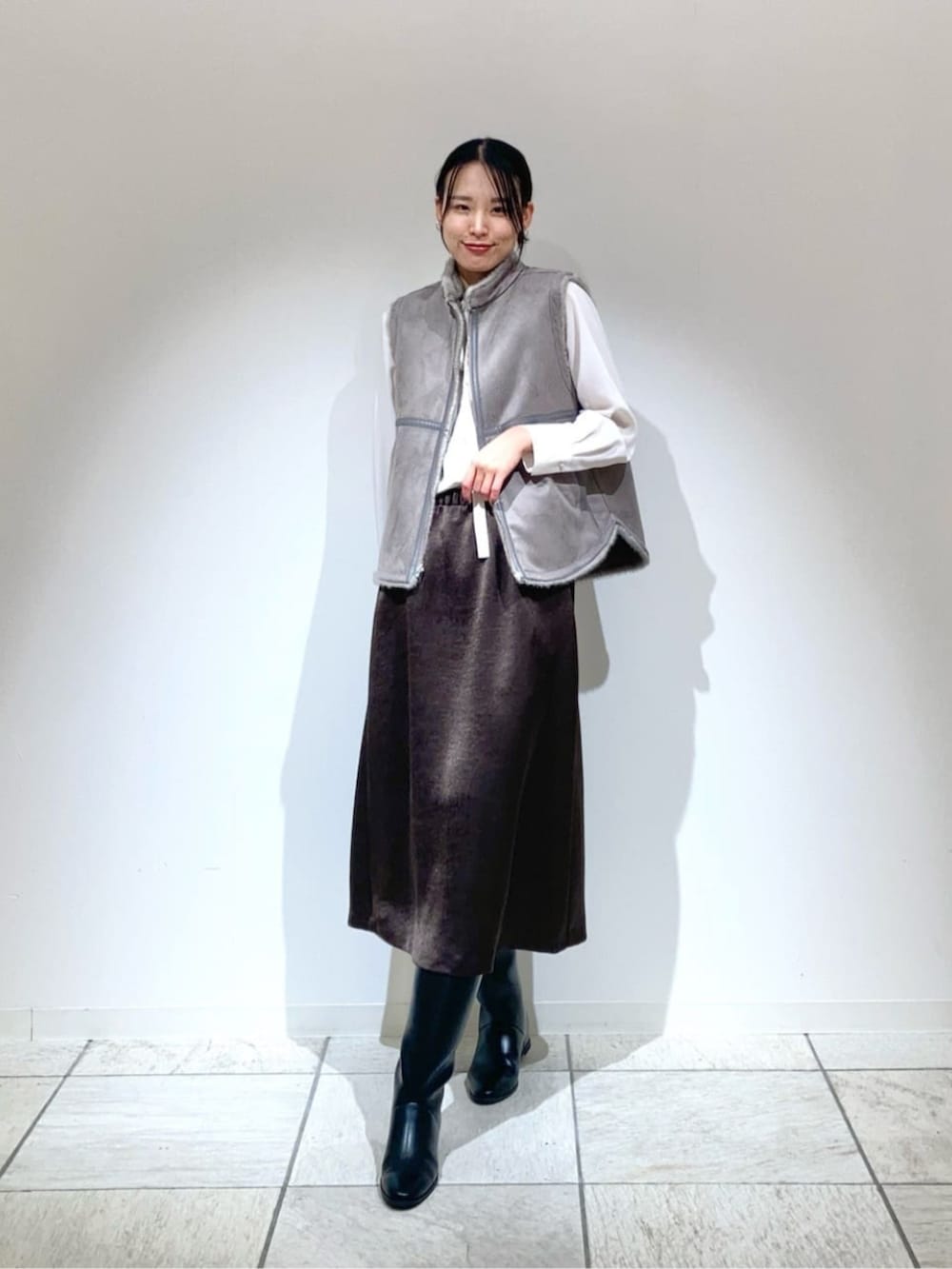 ベージュ系のベスト、ブラック系のスカート、ホワイト系のシャツ/ブラウスを着用したレディースの冬コーディネートの2枚目の写真