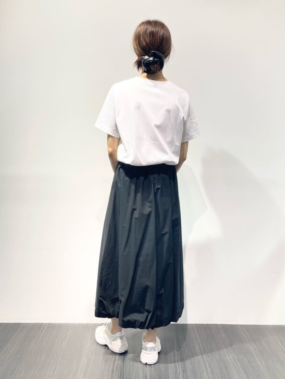 ブラック系のスカート、グレー系のトートバッグ、ホワイト系のTシャツ/カットソーを着用したレディースの夏コーディネートの3枚目の写真