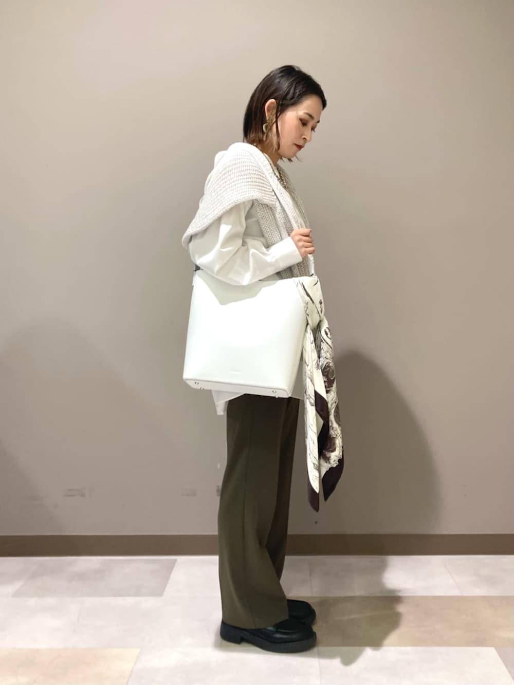 ホワイト系のショルダーバッグ、ホワイト系のシャツ/ブラウス、ブルー系のニット/セーターを着用したレディースの春コーディネートの2枚目の写真