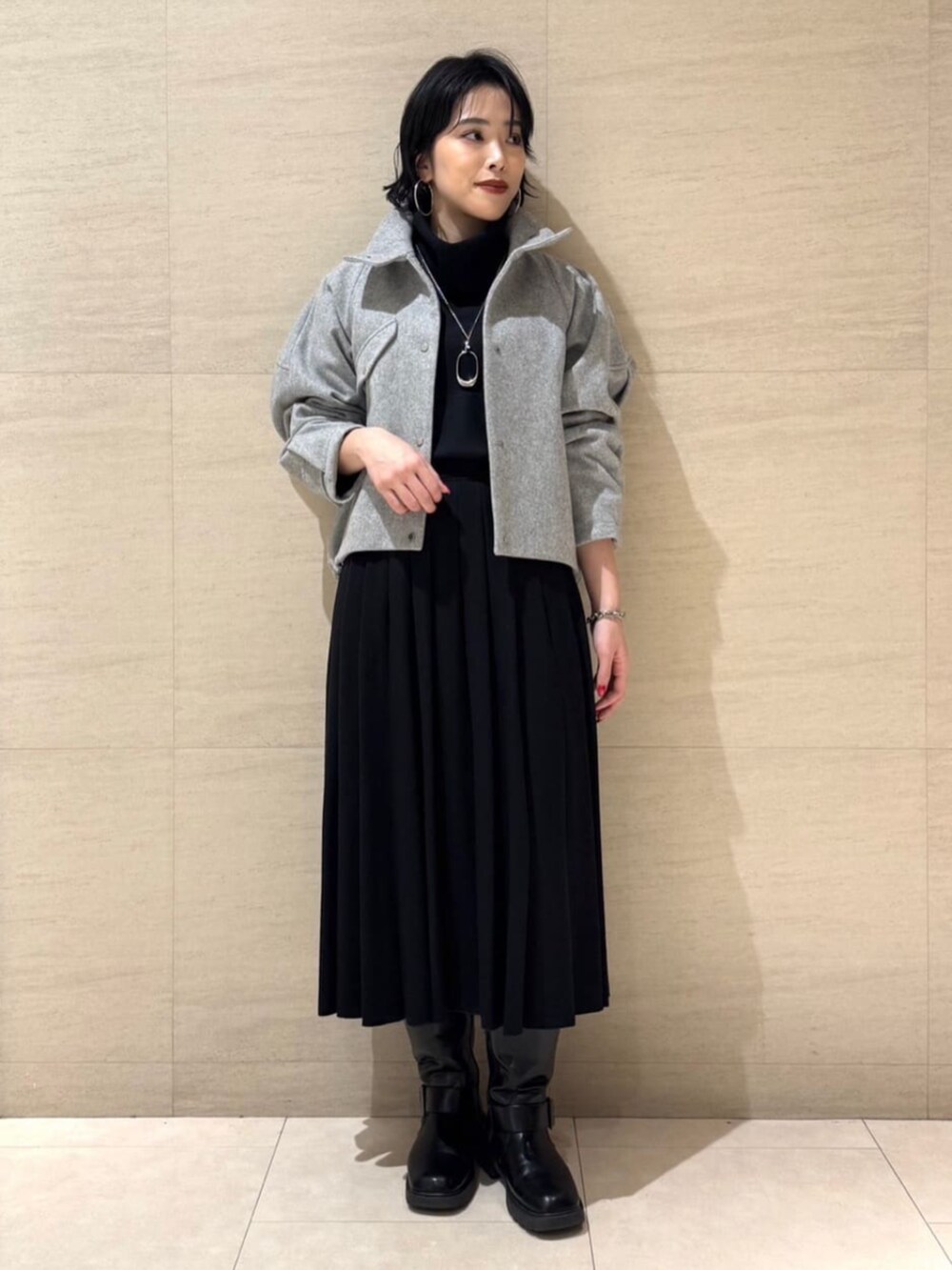 グレー系のブルゾン、ブラック系のTシャツ/カットソー、ブラック系のスカートを着用したレディースの冬コーディネートの3枚目の写真