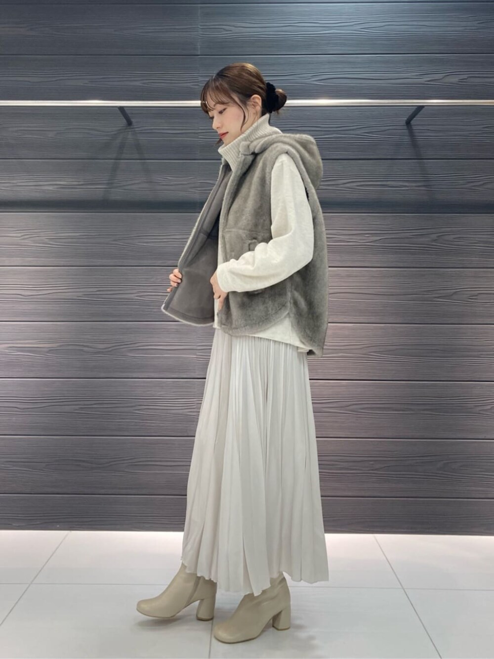 ベージュ系のベスト、ホワイト系のブーツ、ホワイト系のスカートを着用したレディースの秋コーディネートの6枚目の写真