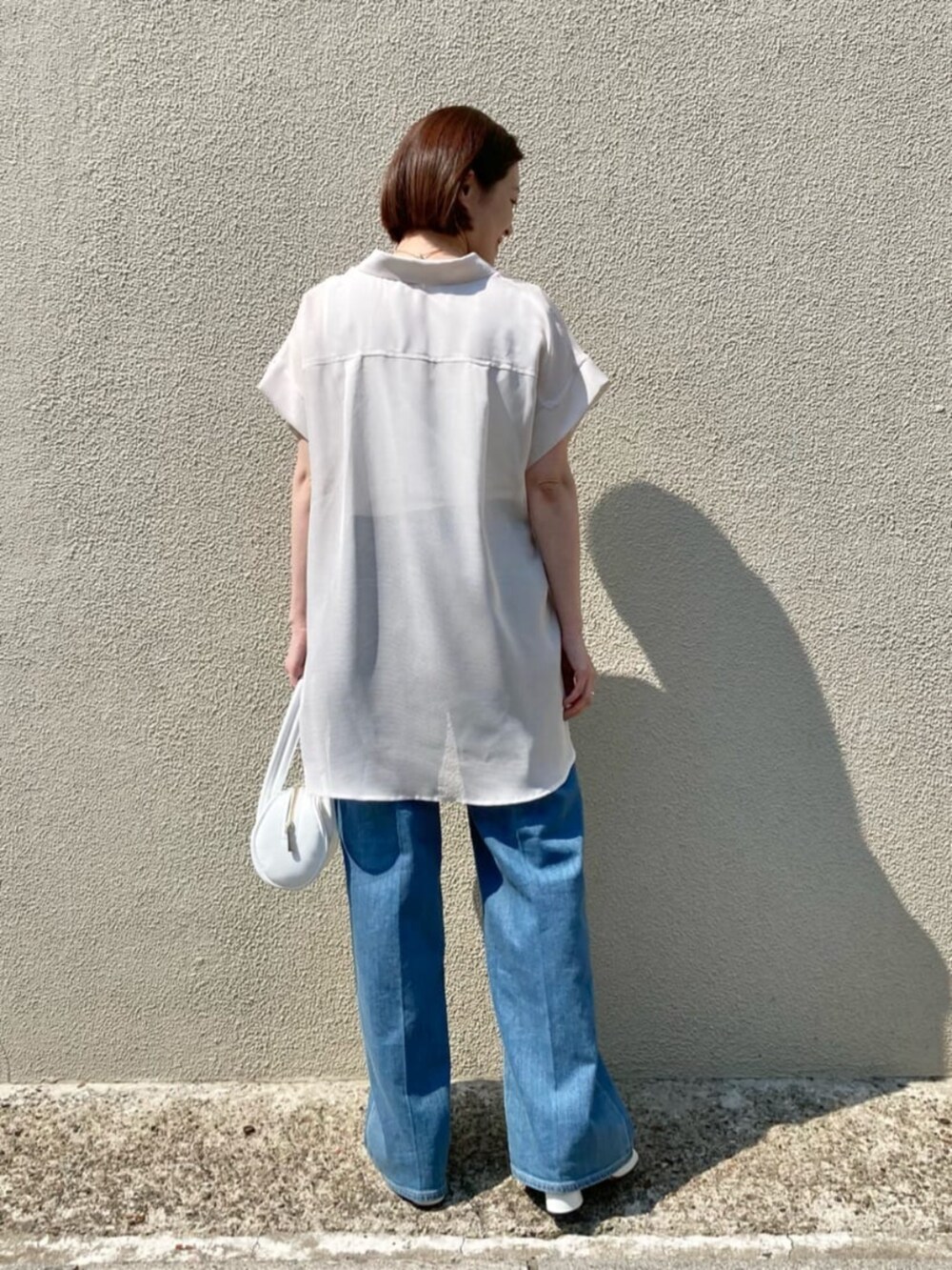 ブルー系のデニムパンツ、ホワイト系のサンダル、ホワイト系のシャツ/ブラウスを着用したレディースの夏コーディネートの4枚目の写真