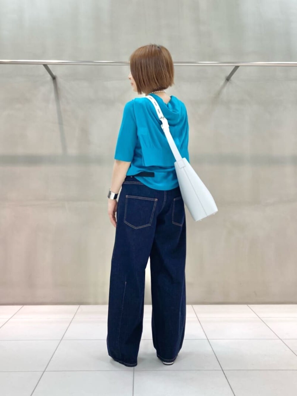 ホワイト系のショルダーバッグ、ブルー系のデニムパンツ、グリーン系のカーディガン/ボレロを着用したレディースの春コーディネートの3枚目の写真