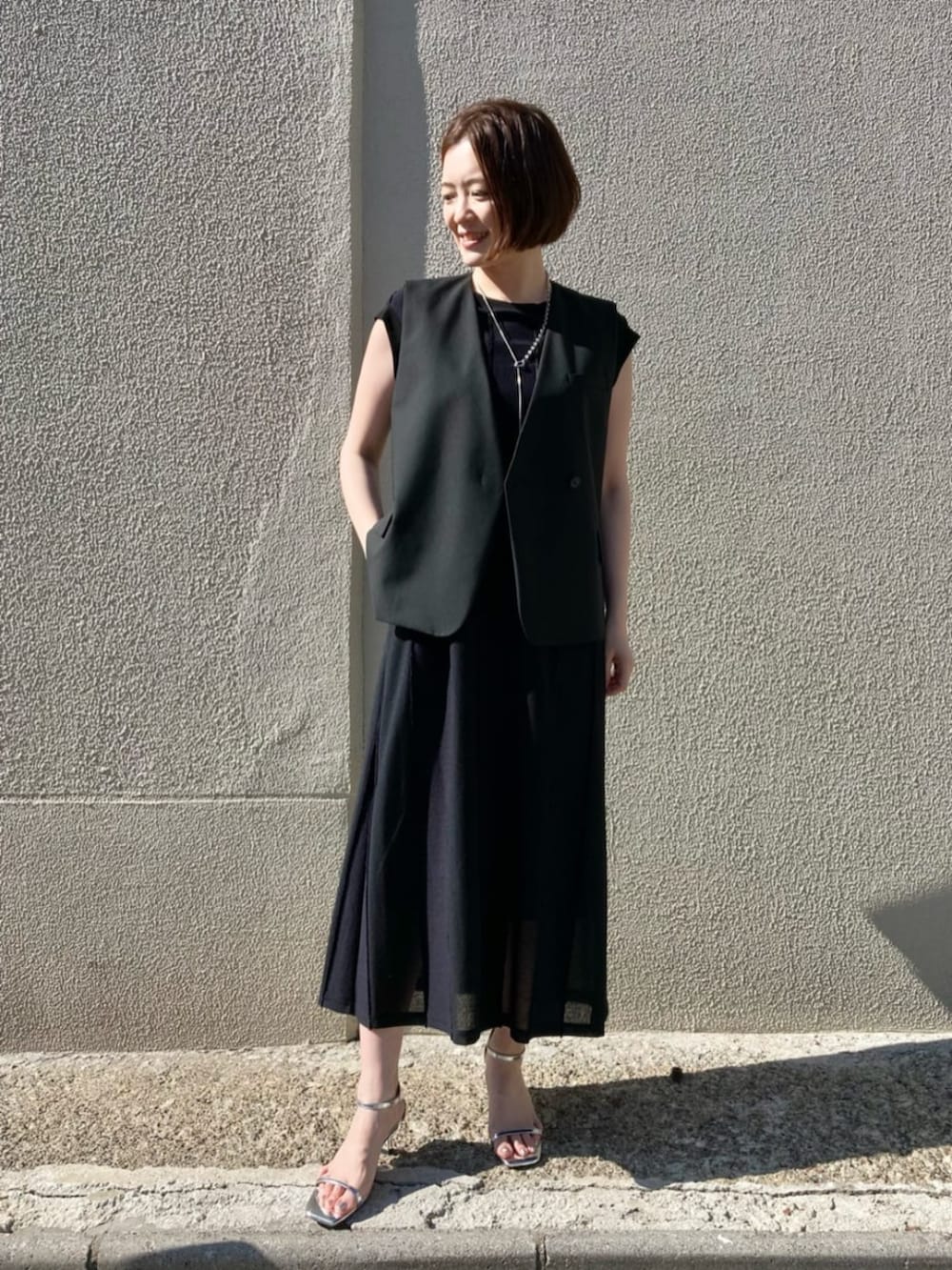 ブラック系のベストを着用したレディースの夏コーディネートの2枚目の写真