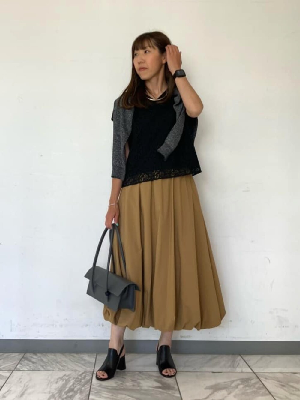 ブラック系のシャツ/ブラウス、ブラック系のサンダル、グレー系のスカートを着用したレディースの春コーディネートの2枚目の写真