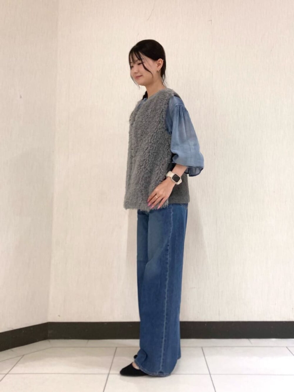 グレー系のベスト、ブルー系のデニムパンツを着用したレディースの秋コーディネートの3枚目の写真
