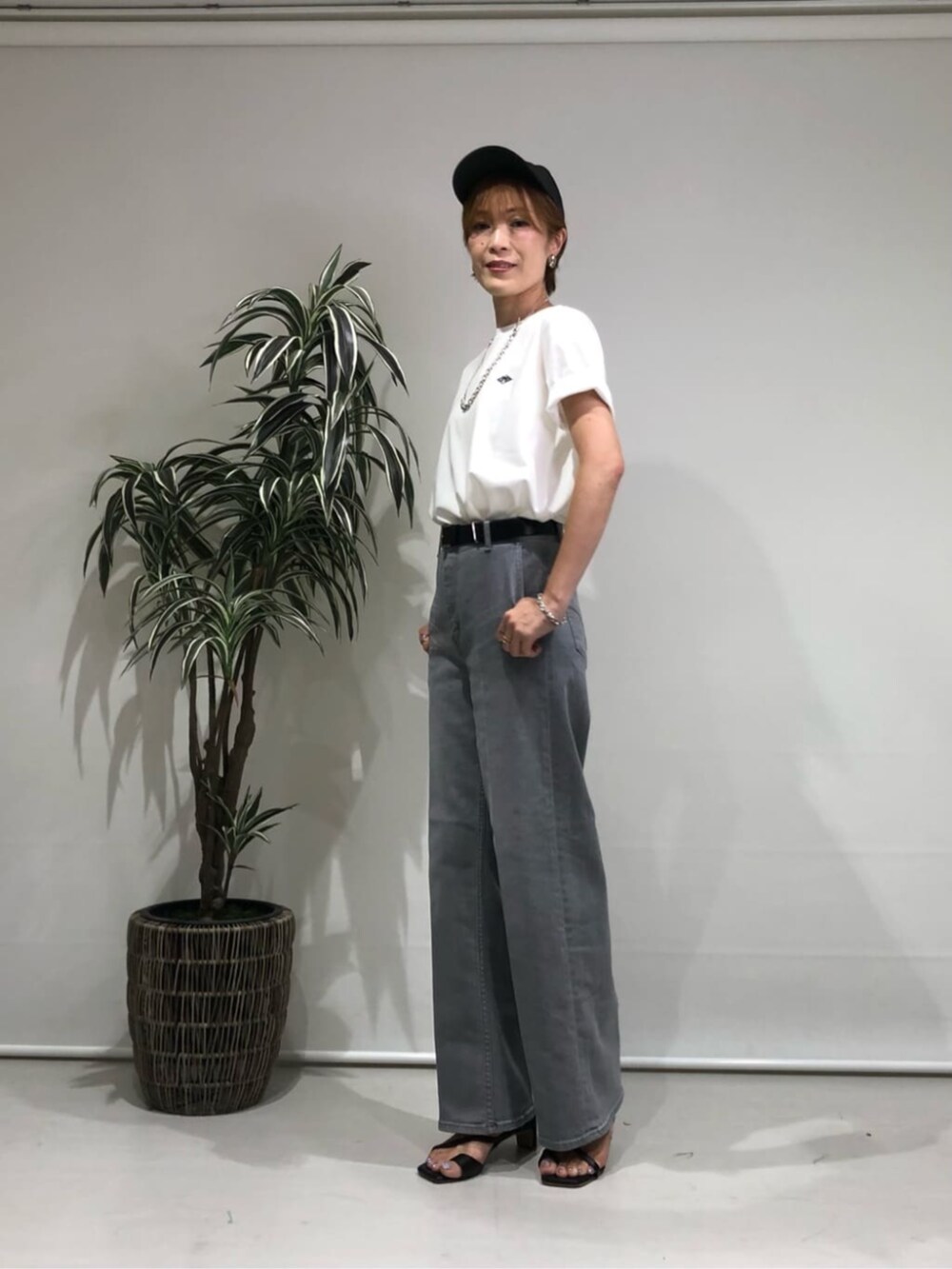 グレー系のデニムパンツ、ホワイト系のトップス、ブラック系のベルトを着用したレディースの夏コーディネートの2枚目の写真