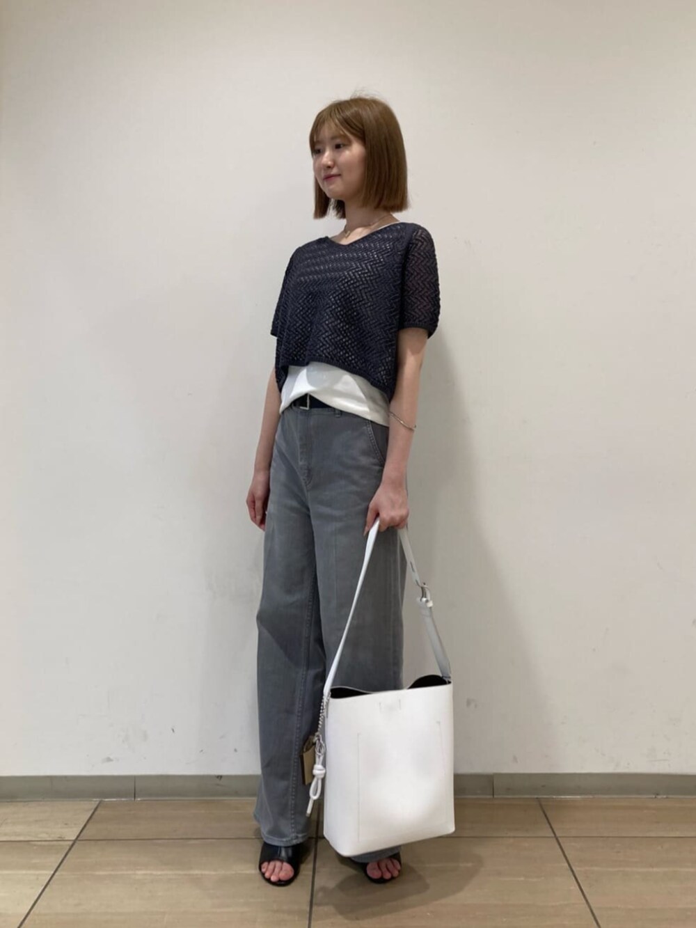 ホワイト系のショルダーバッグ、グレー系のデニムパンツ、グレー系のアンサンブルを着用したレディースの秋コーディネートの2枚目の写真