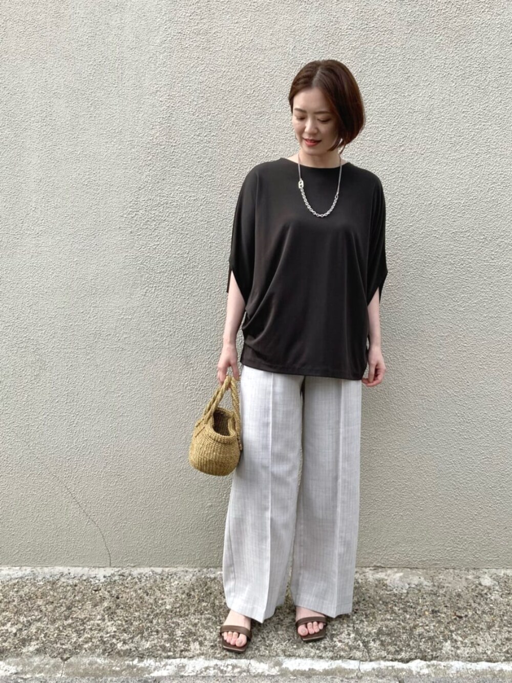 ホワイト系のスラックス、シルバー系のネックレスを着用したレディースの夏コーディネートの2枚目の写真