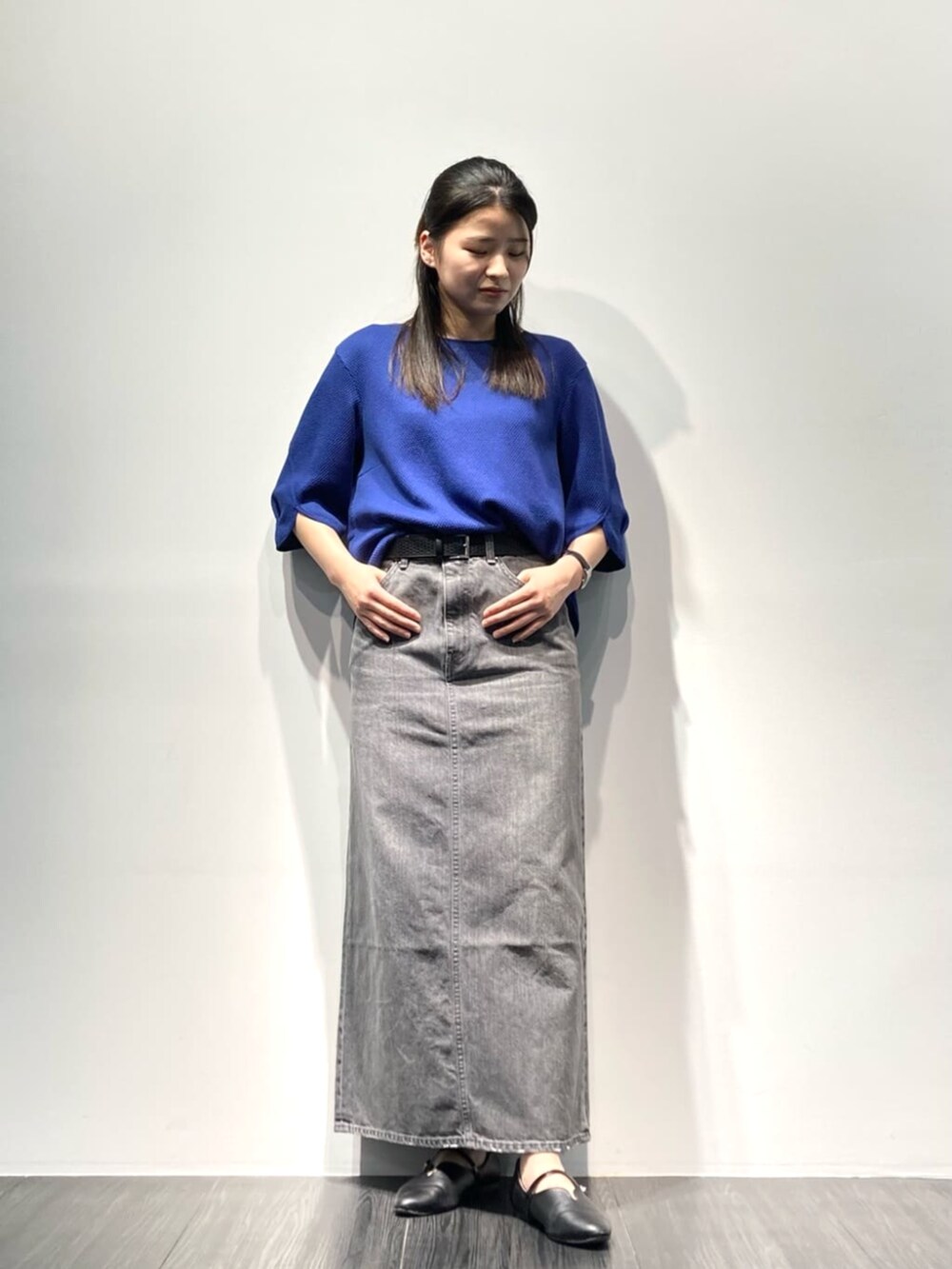 グレー系のスカート、ブルー系のTシャツ/カットソー、ブラック系のベルトを着用したレディースの春コーディネートの2枚目の写真