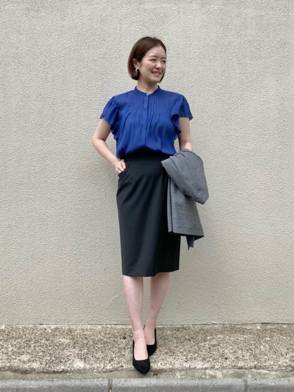 ブルー系のシャツ/ブラウス、グレー系のテーラードジャケット、ブラック系のスーツスカートを着用したレディースの秋コーディネートの6枚目の写真