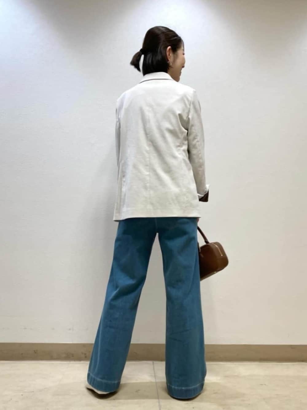 ブルー系のデニムパンツ、ホワイト系のテーラードジャケット、ブラック系のボストンバッグを着用したレディースの春コーディネートの4枚目の写真