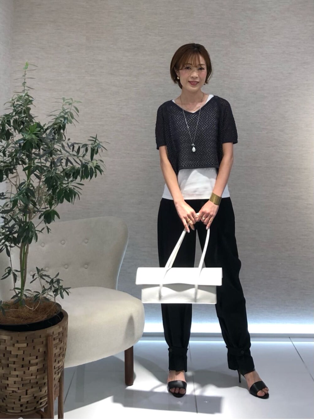 グレー系のアンサンブル、ホワイト系のネックレスを着用したレディースの夏コーディネートの2枚目の写真