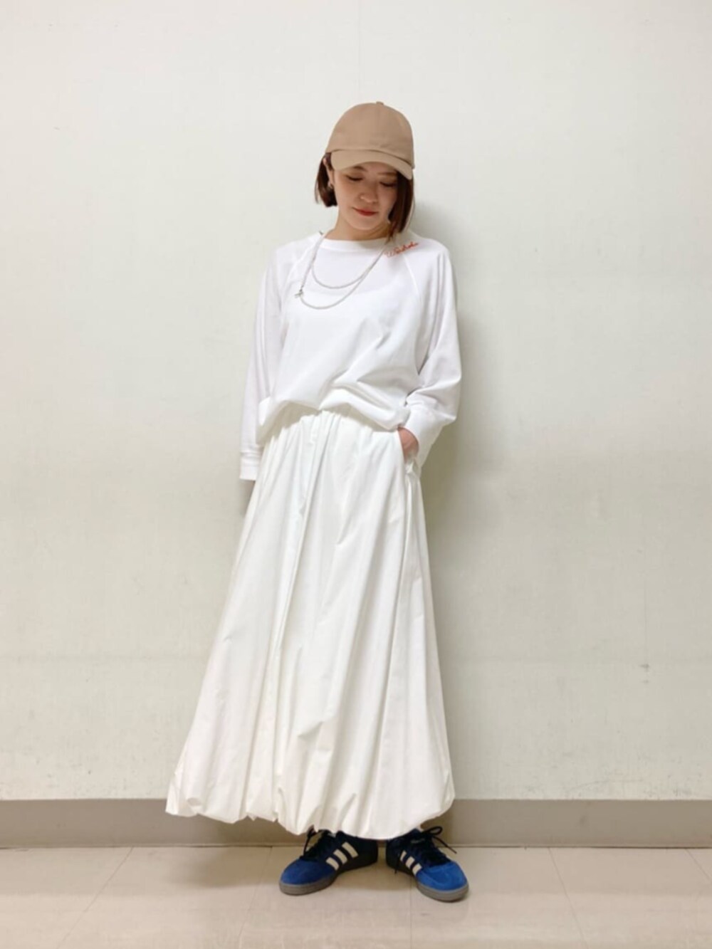 ホワイト系のスカート、ブルー系のブルゾン、イエロー系のキャップを着用したレディースの春コーディネートの5枚目の写真