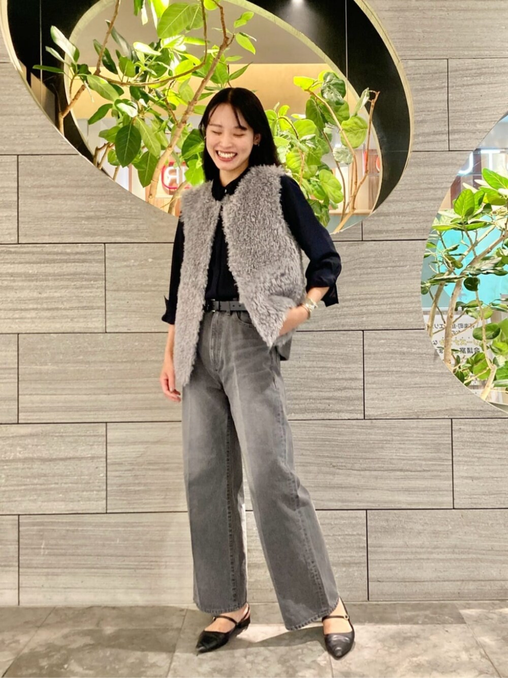 グレー系のデニムパンツ、グレー系のベスト、ブルー系のシャツ/ブラウスを着用したレディースの秋コーディネートの2枚目の写真