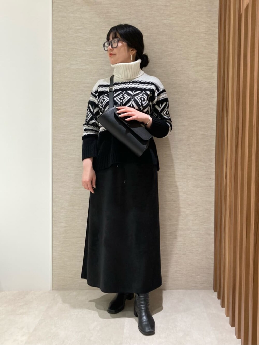 ブラック系のスカート、ブラック系のショルダーバッグ、ブラック系のニット/セーターを着用したレディースの冬コーディネートの2枚目の写真