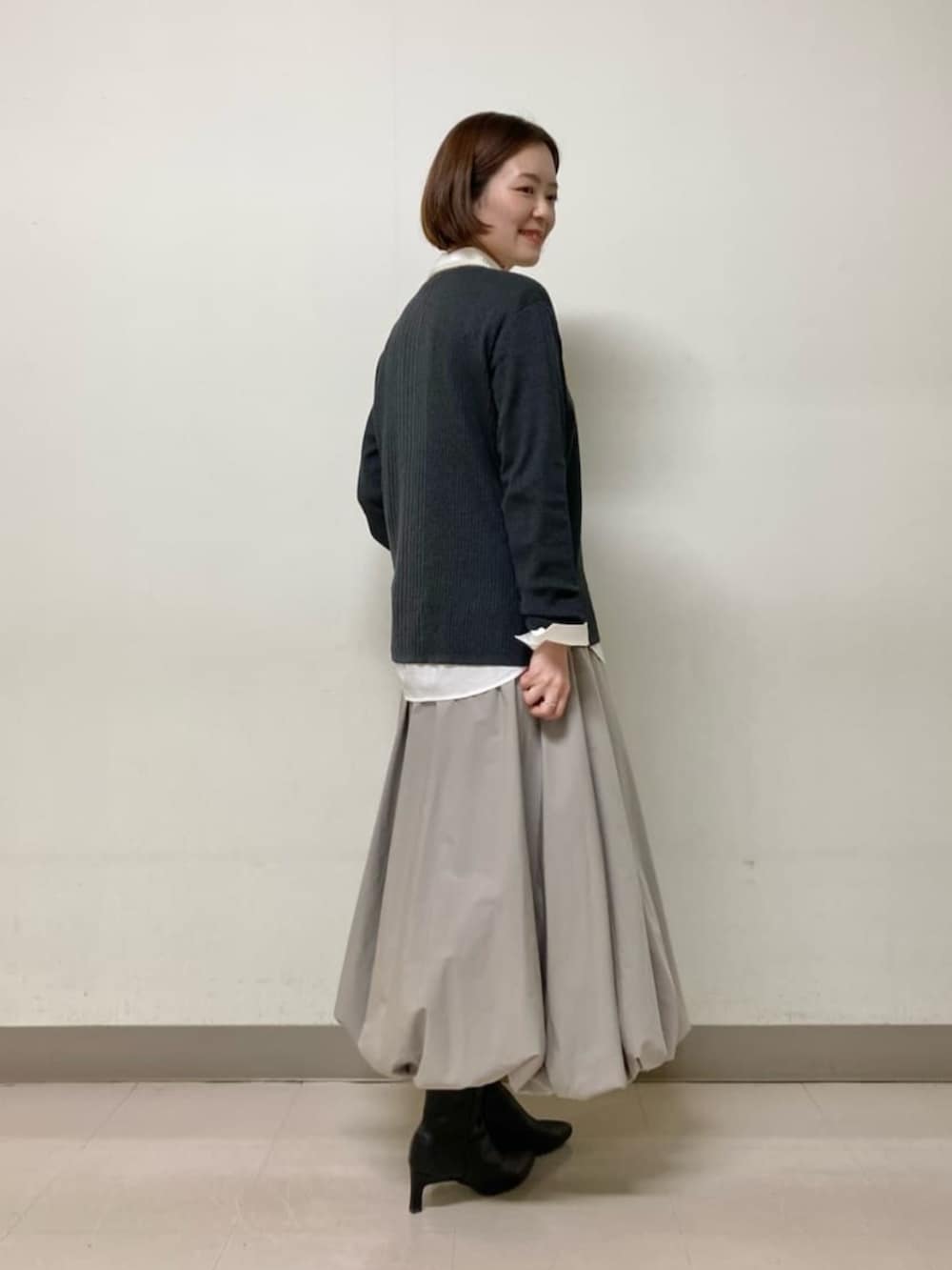 ベージュ系のスカート、グレー系のニット/セーター、ホワイト系のシャツ/ブラウスを着用したレディースの冬コーディネートの5枚目の写真