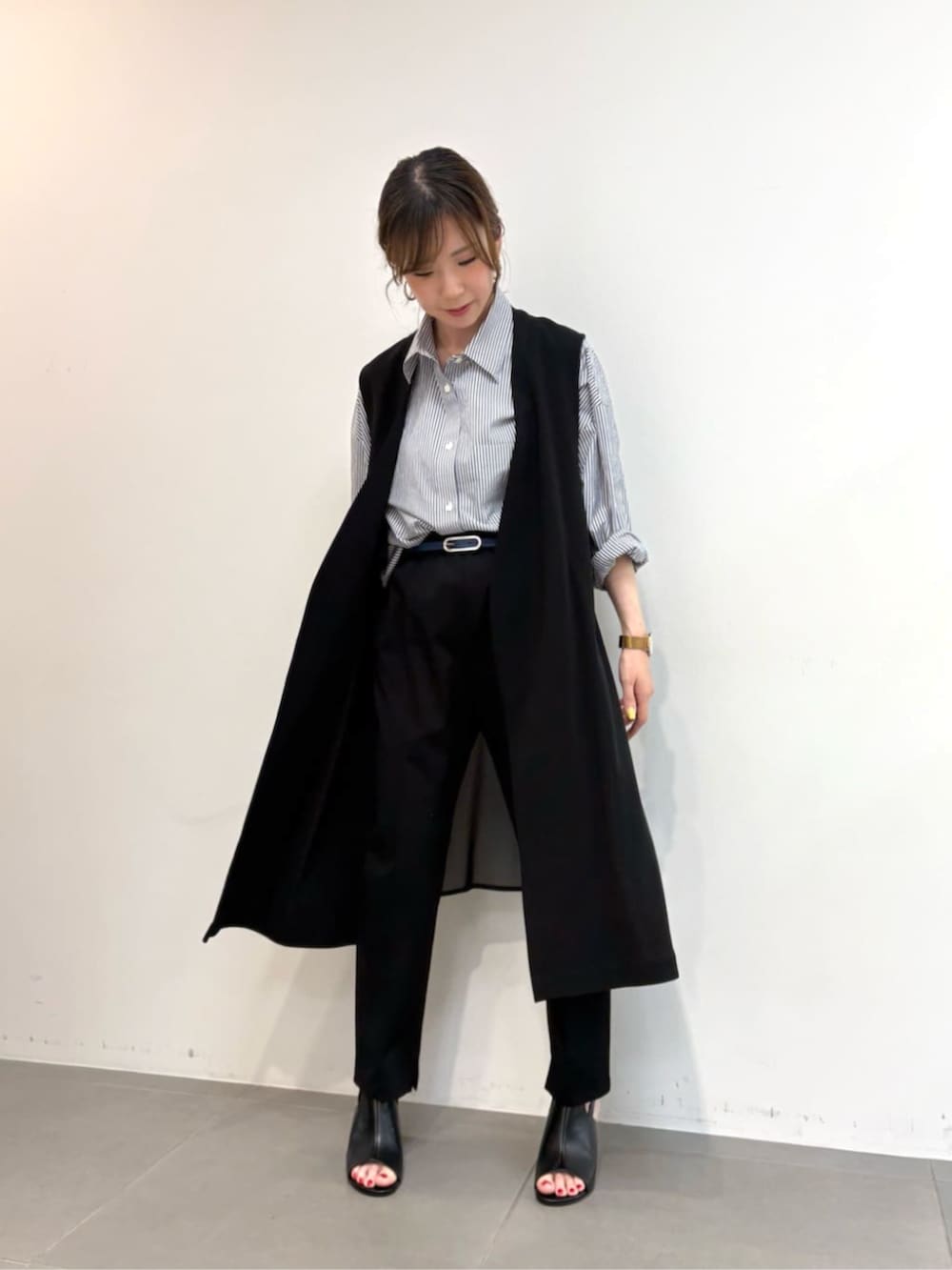 ブルー系のシャツ/ブラウス、ブラック系のサンダル、ブラック系のベストを着用したレディースの春コーディネートの4枚目の写真