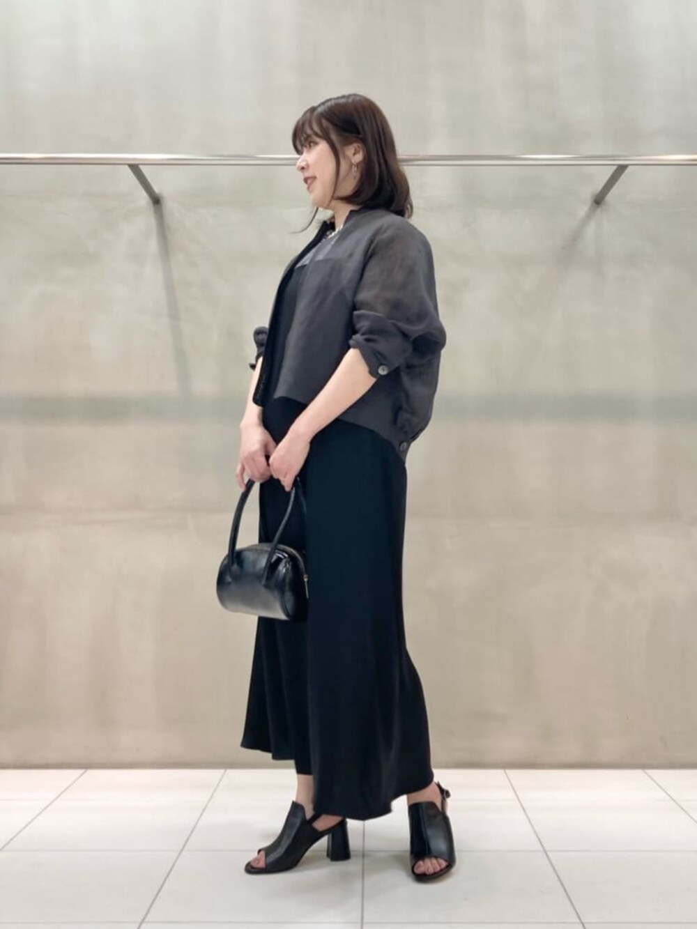 ブラック系のサンダル、ブラック系のワンピース、シルバー系のネックレスを着用したレディースの夏コーディネートの3枚目の写真