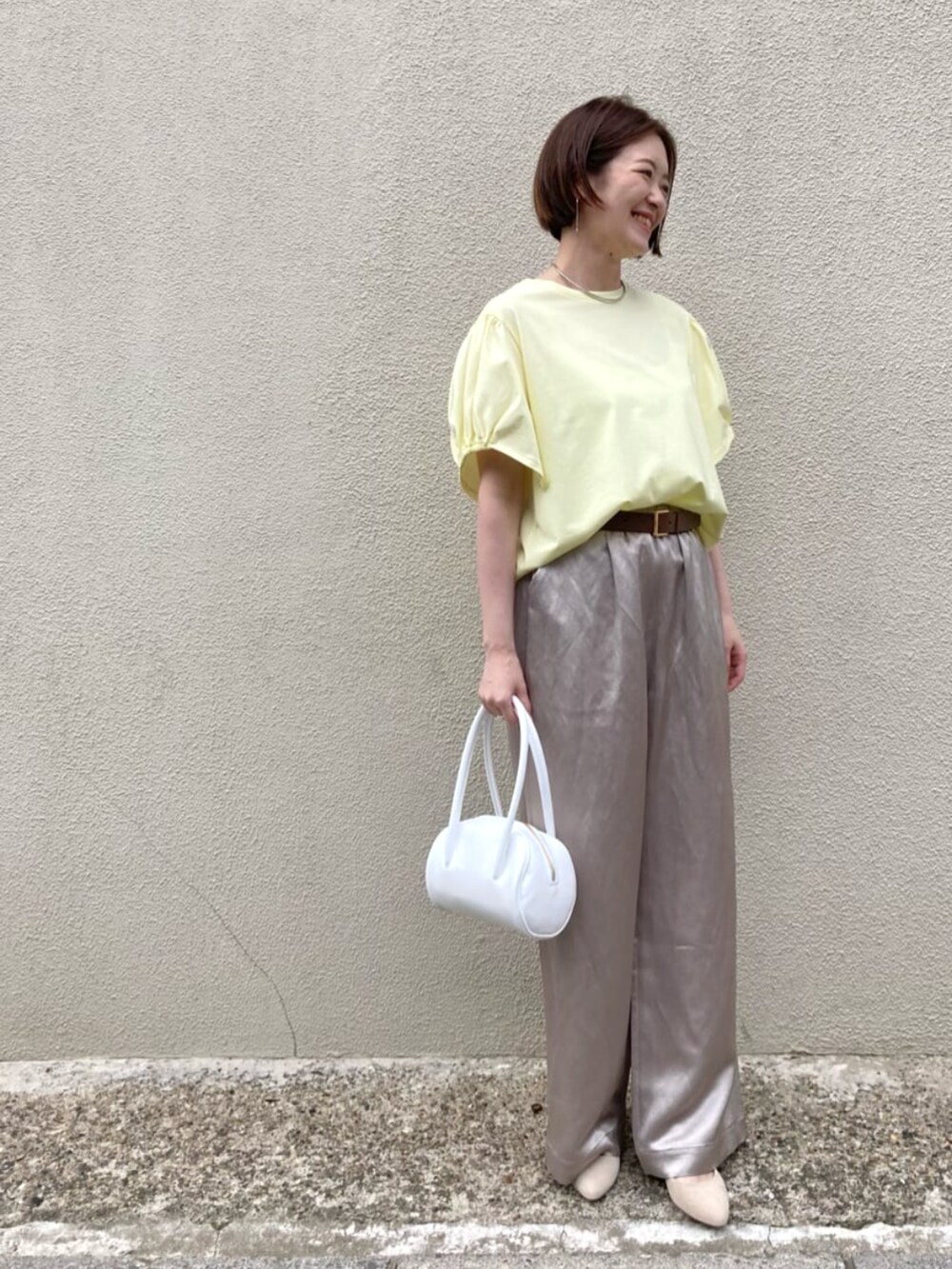 イエロー系のTシャツ/カットソー、ベージュ系のその他パンツ、ホワイト系のバッグを着用したレディースの夏コーディネートの2枚目の写真