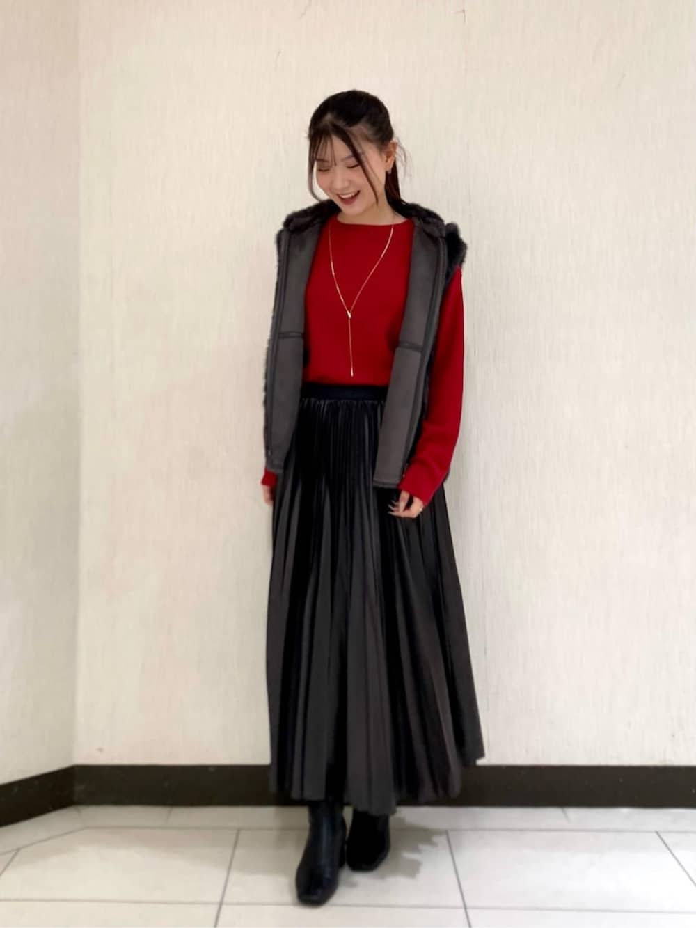 グレー系のベスト、グレー系のスカート、レッド系のニット/セーターを着用したレディースの秋コーディネートの2枚目の写真