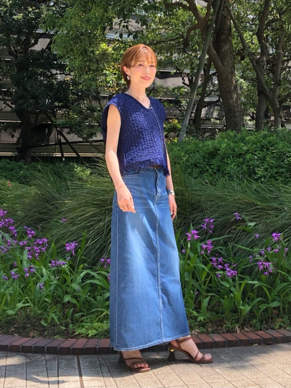 グレー系のスカート、ブルー系のニット/セーター、ブラウン系のベルトを着用したレディースの春コーディネートの2枚目の写真