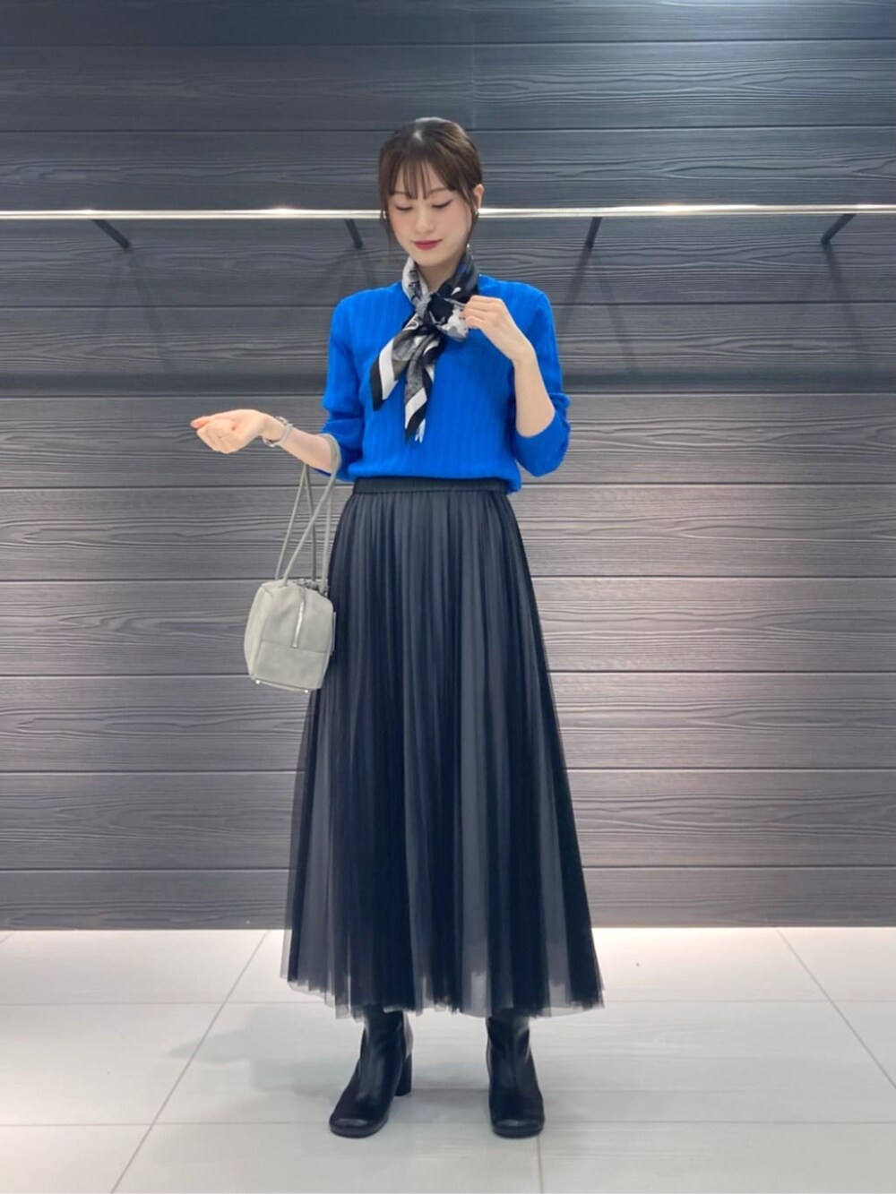 グレー系のスカート、グレー系のその他アウター、ブルー系のニット/セーターを着用したレディースの秋コーディネートの4枚目の写真