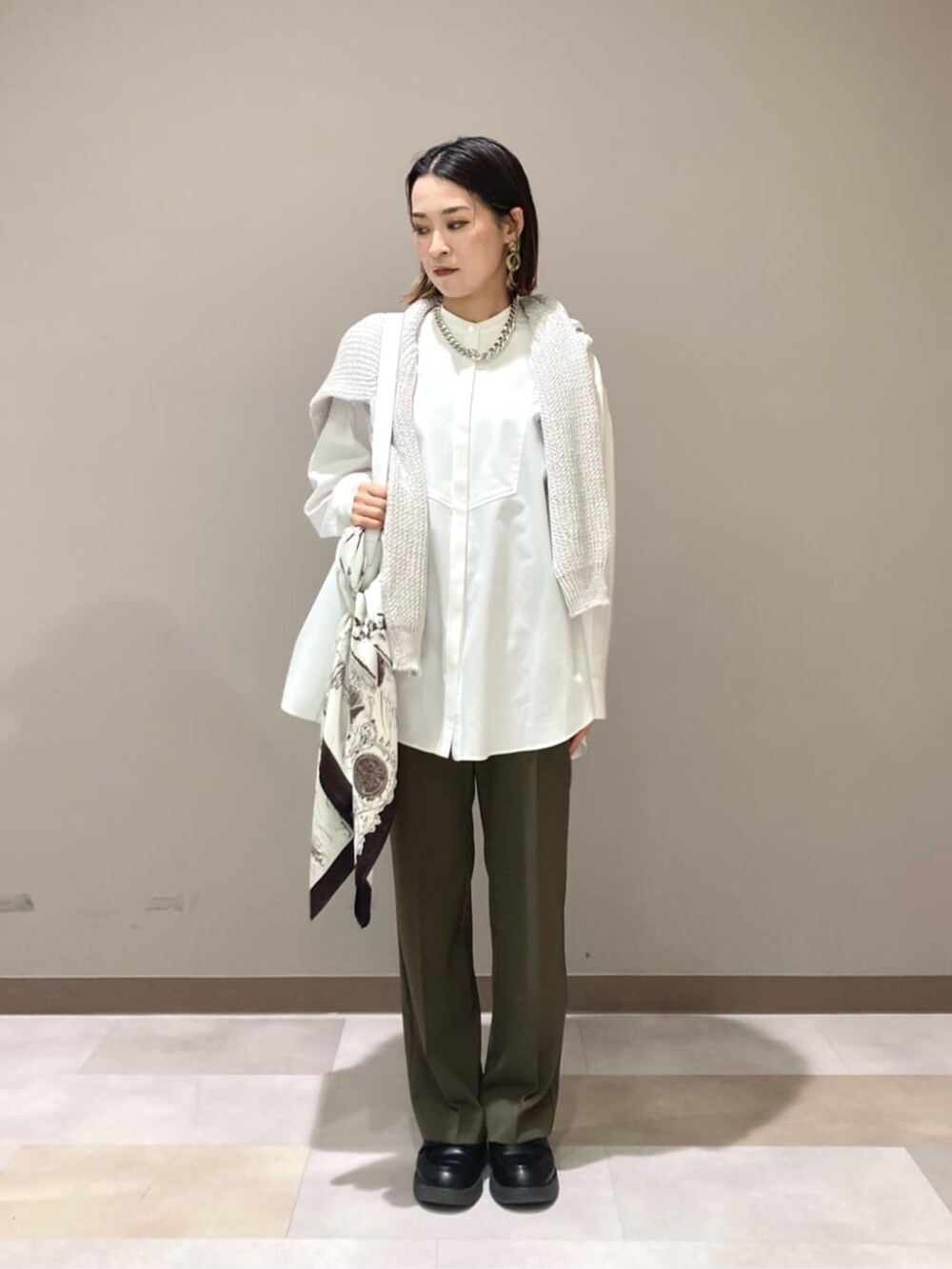 ホワイト系のショルダーバッグ、ホワイト系のシャツ/ブラウス、ブルー系のニット/セーターを着用したレディースの春コーディネートの3枚目の写真