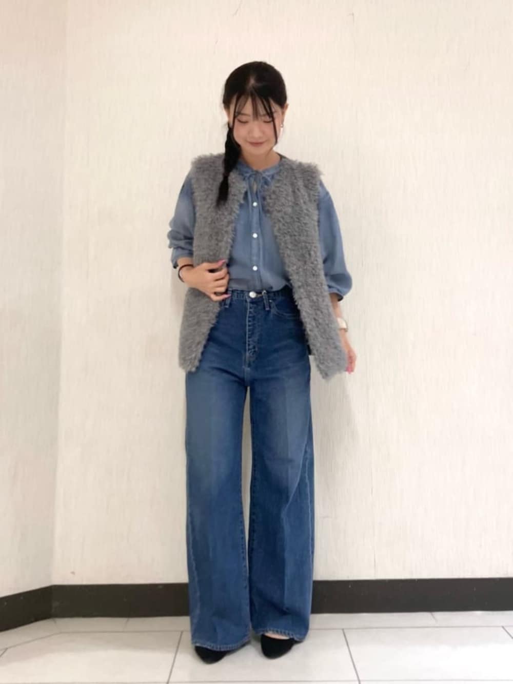 グレー系のベスト、ブルー系のデニムパンツを着用したレディースの秋コーディネートの2枚目の写真