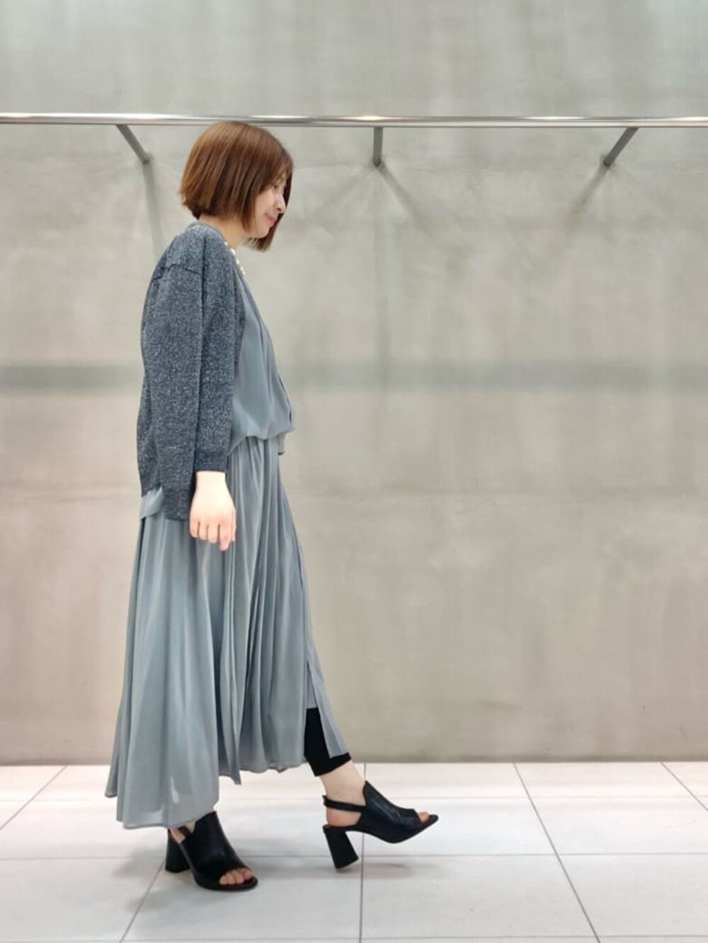 ブラック系のサンダル、グレー系のカーディガン/ボレロ、グリーン系のスカートを着用したレディースの春コーディネートの2枚目の写真