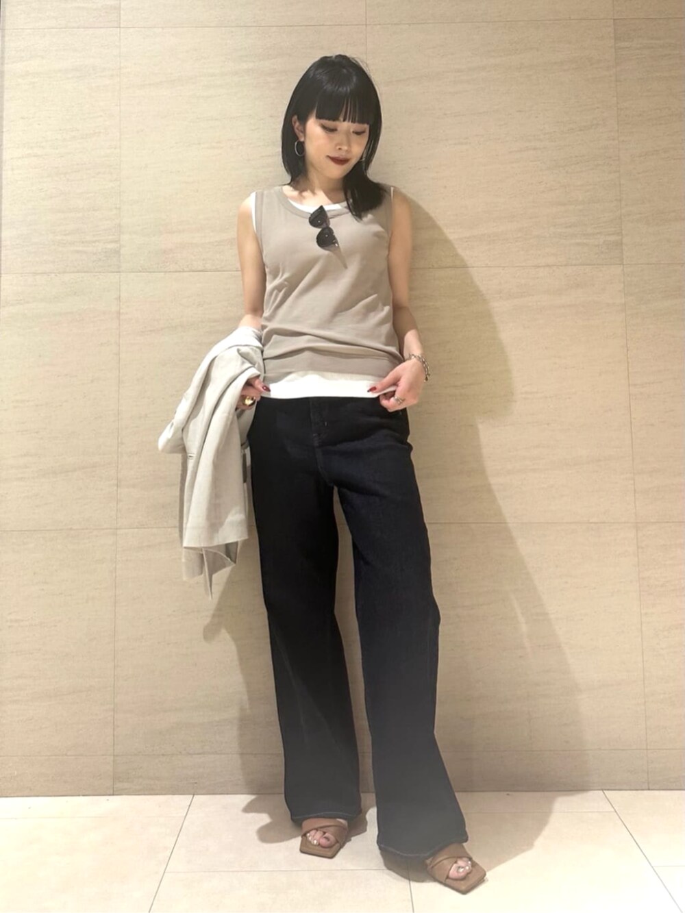 ブルー系のデニムパンツ、ベージュ系のテーラードジャケット、ベージュ系のタンクトップを着用したレディースの夏コーディネートの4枚目の写真