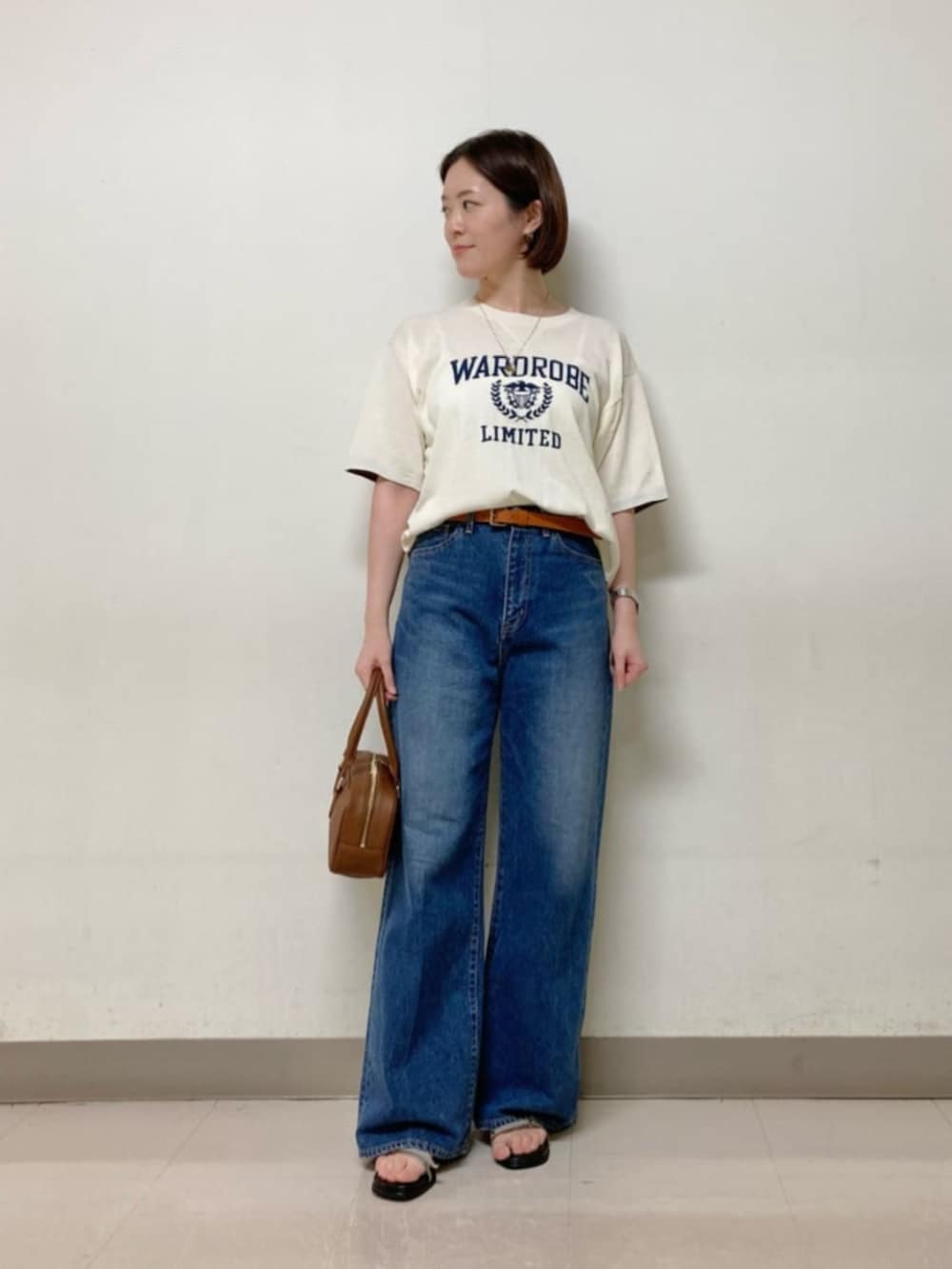 ブラウン系のボストンバッグ、ブルー系のデニムパンツ、ホワイト系のニット/セーターを着用したレディースの春コーディネートの4枚目の写真