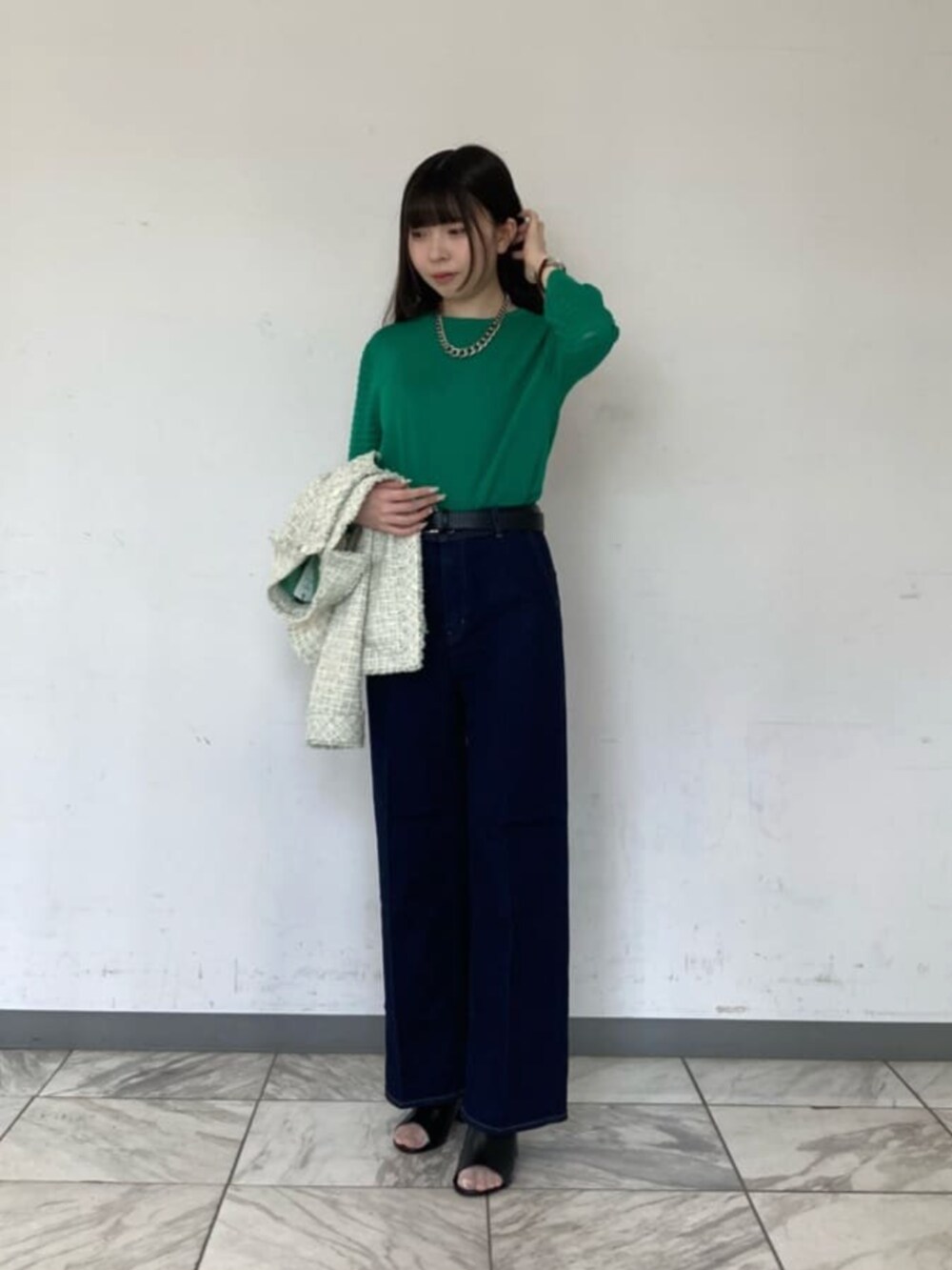 ブルー系のデニムパンツ、グリーン系のニット/セーター、ブラック系のサンダルを着用したレディースの春コーディネートの2枚目の写真