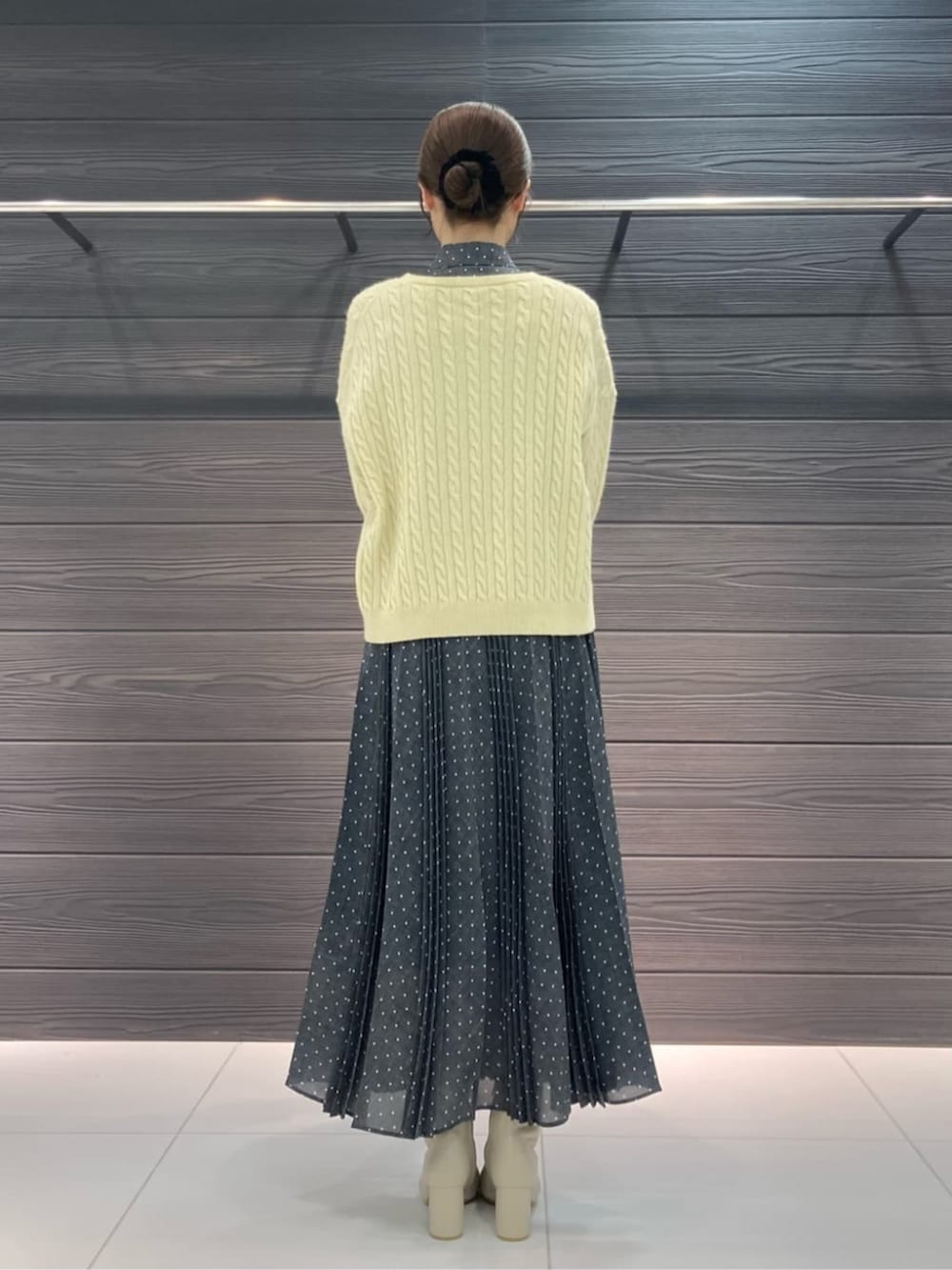 ホワイト系のブーツ、イエロー系のニット/セーター、グレー系のスカートを着用したレディースの冬コーディネートの4枚目の写真