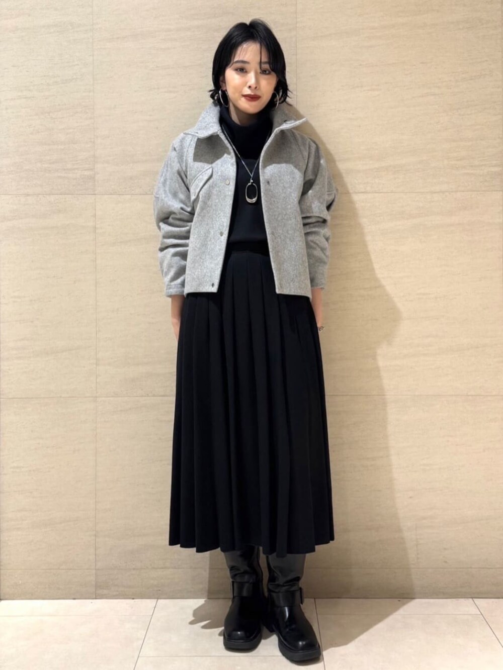 グレー系のブルゾン、ブラック系のTシャツ/カットソー、ブラック系のスカートを着用したレディースの冬コーディネートの2枚目の写真