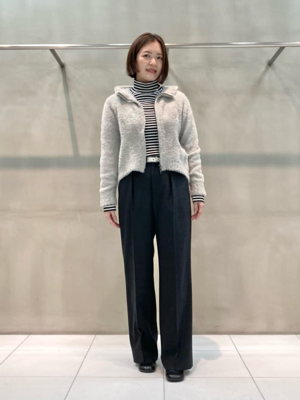 グレー系のスーツパンツ、ブラック系のブーツ、ベージュ系のパーカーを着用したレディースの秋コーディネートの3枚目の写真