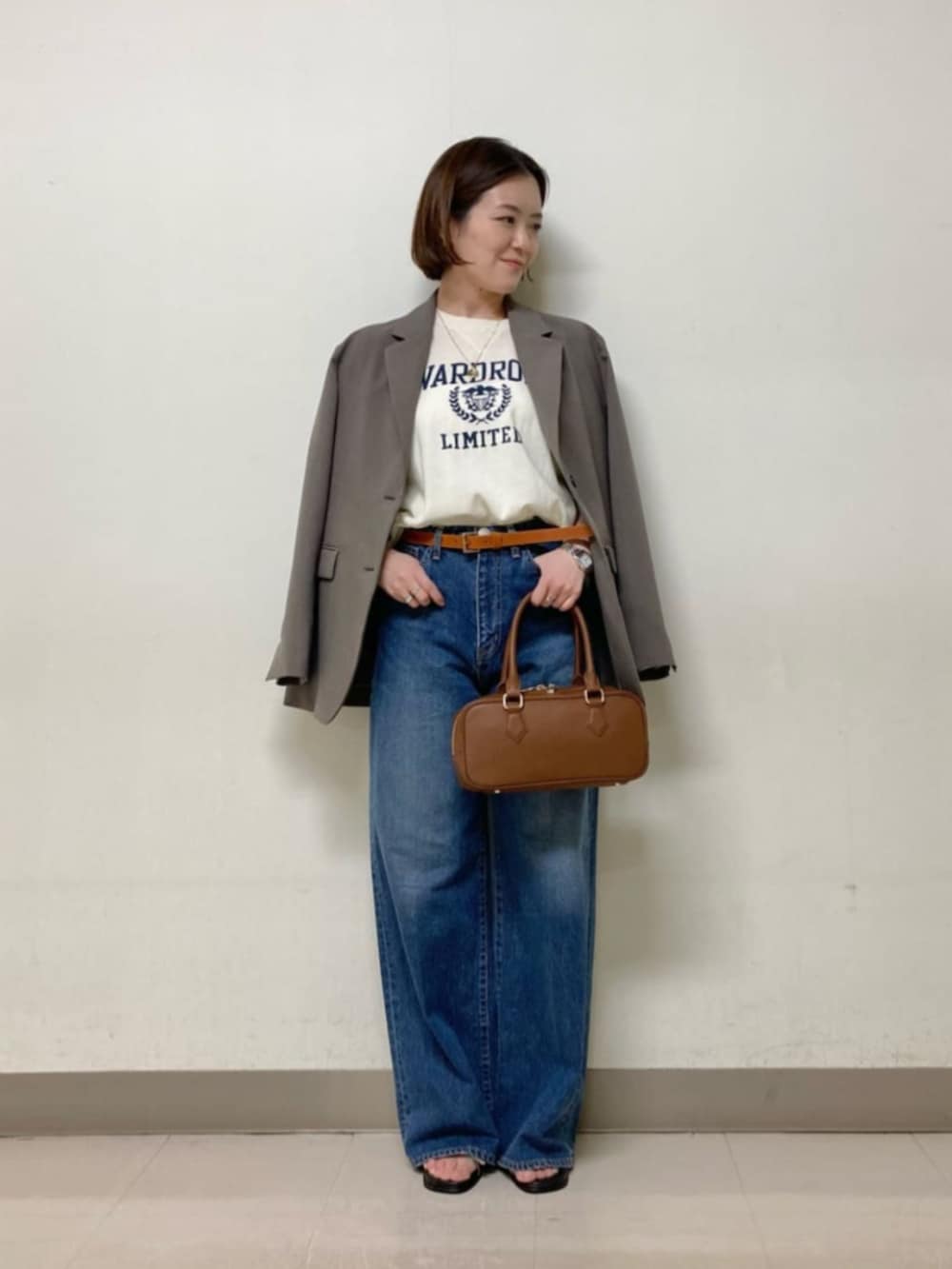 ブラウン系のボストンバッグ、ブルー系のデニムパンツ、ホワイト系のニット/セーターを着用したレディースの春コーディネートの3枚目の写真