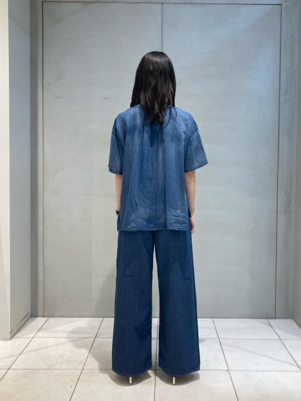 ブラウン系のクラッチバッグ、ブルー系のシャツ/ブラウス、ブルー系のデニムパンツを着用したレディースの夏コーディネートの5枚目の写真