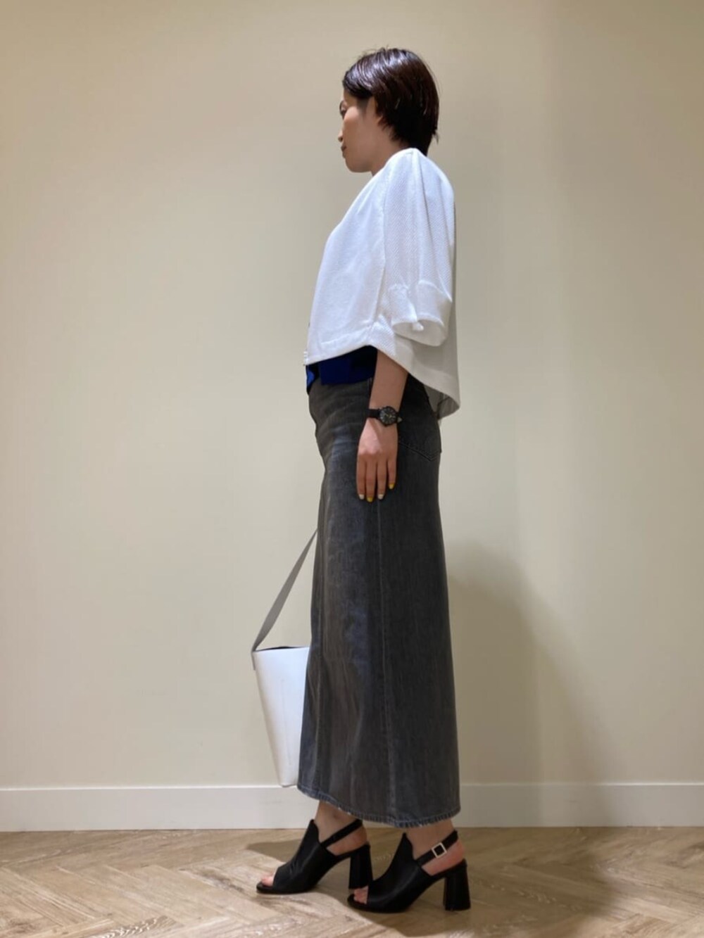 ホワイト系のショルダーバッグ、ブルー系のTシャツ/カットソー、グレー系のスカートを着用したレディースの夏コーディネートの2枚目の写真