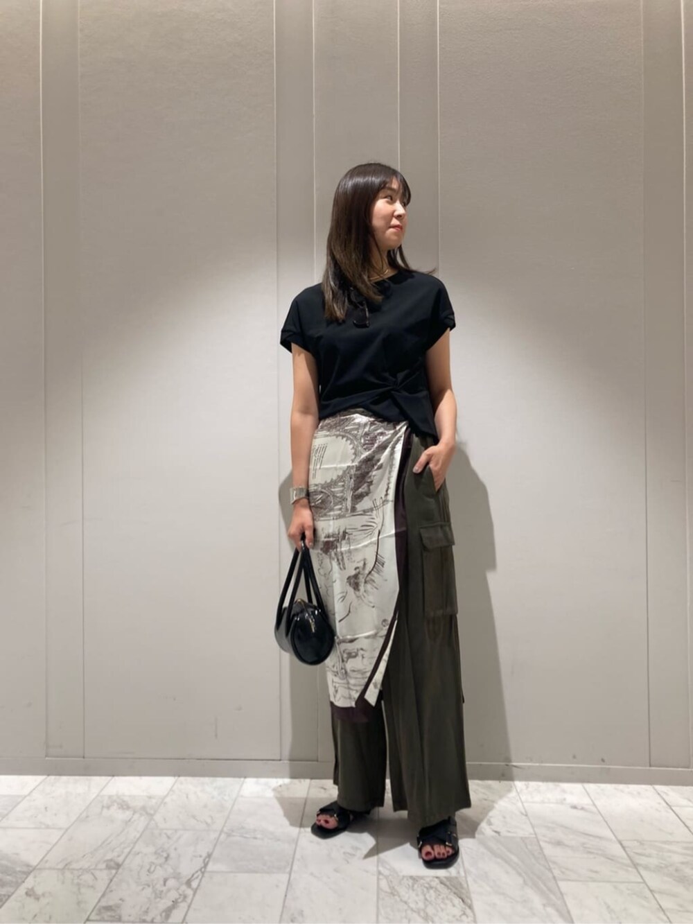 グリーン系のその他パンツ、ブラック系のTシャツ/カットソー、ブラウン系のストール/ショールを着用したレディースの秋コーディネートの2枚目の写真