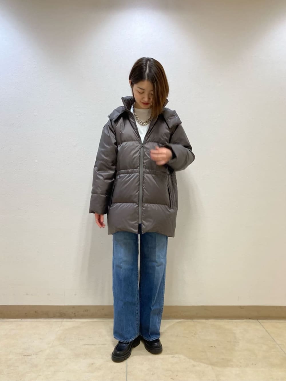 ブルー系のデニムパンツ、グレー系のダウンジャケット/コート、ベージュ系のカーディガン/ボレロを着用したレディースの冬コーディネートの4枚目の写真