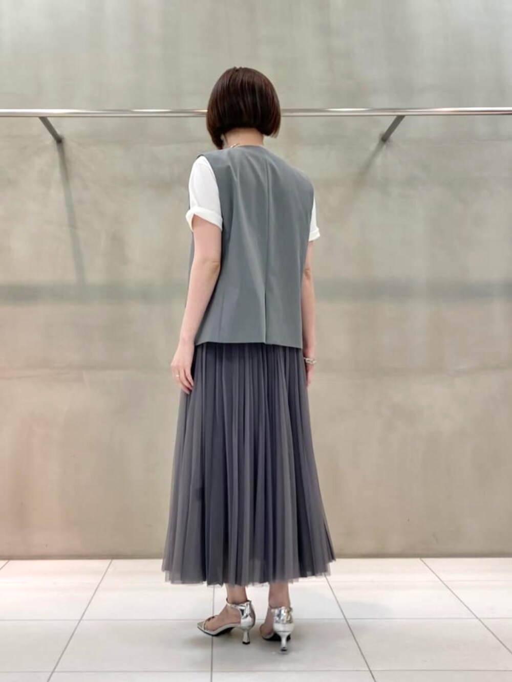 ブルー系のスカート、ホワイト系のTシャツ/カットソー、ブラック系のベストを着用したレディースの春コーディネートの4枚目の写真