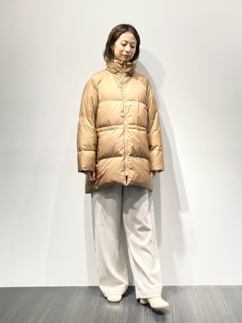 イエロー系のダウンジャケット/コート、ベージュ系のその他パンツ、ホワイト系のブーツを着用したレディースの秋コーディネートの3枚目の写真