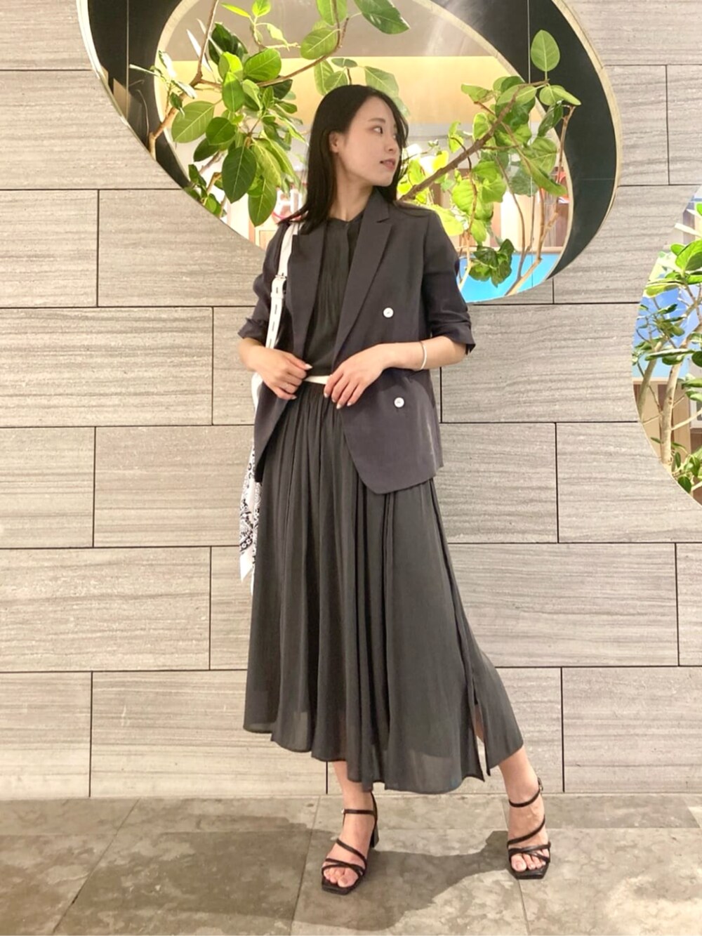 ホワイト系のショルダーバッグ、グレー系のテーラードジャケット、グリーン系のスカートを着用したレディースの春コーディネートの2枚目の写真