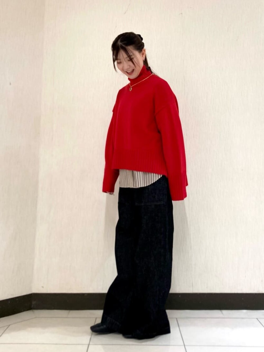 レッド系のニット/セーター、ブラック系のデニムパンツを着用したレディースの冬コーディネートの2枚目の写真